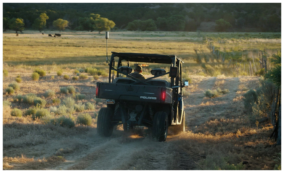 Utility side by side with the weBoost SxS antenna moving cattle