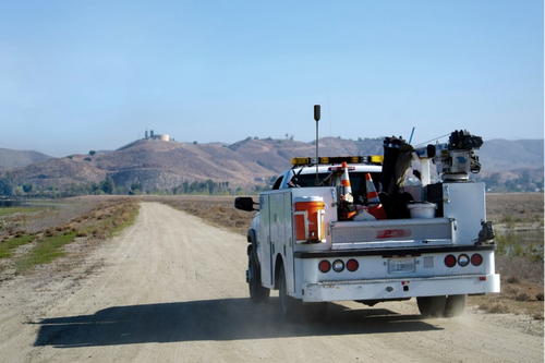 Truck with equipment on a dirt road under a clear blue sky